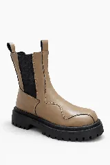 Botas color beige con caña desmontable, suela track negra y elásticos laterales negros.