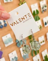 Aros tipo argolla de acero con dije colgante de esfera de cristal facetado en color verde traslúcido.