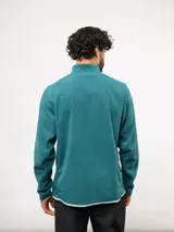 Buzo de entrenamiento Umbro con medio cierre frontal, cuello alto y bolsillo en el pecho de nylon con cierre. Presenta una textura sutil en el tejido y logo de la marca estampado en el bolsillo.