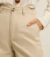 Bermuda color beige de sastrería, confeccionada en sarga de algodón, con cintura mediana, trabillas, cierre tradicional y bolsillos.