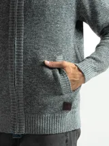 Campera de punto con cierre frontal, cuello alto y forro interno. Presenta un diseño de tejido jaspeado con puños y ruedo acanalados, e incluye un pequeño aplique de marca en la parte inferior.