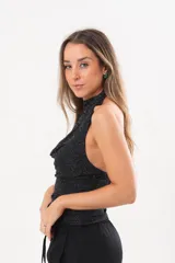 Top de lurex negro con cuello halter drapeado y acabado brillante.