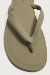 Sandalia plana de goma, color verde oscuro con tiras cruzadas en el empeine en tono beige.