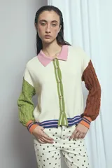 Cardigan de punto color marrón, con cuello vuelto, cierre frontal de botones y detalles de ribetes a rayas en los puños, la cintura y la botonera. Las mangas presentan un diseño tejido en relieve con textura de ochos.