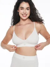 Top deportivo de estilo bralette, confeccionado en tejido seamless acanalado de color verde militar. Presenta breteles finos ajustables, escote en V y una banda elástica inferior con una pequeña etiqueta decorativa central.