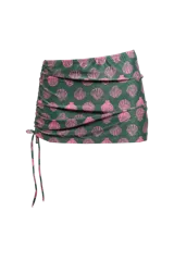 Minifalda de playa color verde con estampado de conchas rosadas, con cordón ajustable en el lateral.