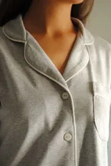 Camisa celeste con cuello clásico, cierre frontal con botones, manga larga con puños abotonados y bolsillo de parche en el pecho.