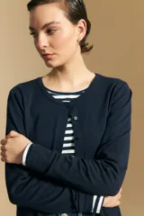 Cardigan de tejido suave y liviano, color azul marino, con cuello redondo y cierre frontal abotonado. Presenta mangas largas con puños ajustados.