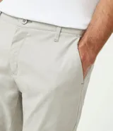 Pantalón de vestir color marrón, de corte slim y largo cropped. Confeccionado en tejido de algodón liso, con bolsillos laterales y traseros. Cierre frontal con botón y cremallera.