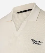 Camisa polo de hombre confeccionada en tejido de punto de algodón, color crema, con cuello en V y manga corta. Presenta un corte oversized y un pequeño bordado de lettering en el pecho.