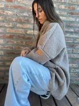 Campera de corderito color verde oscuro, con diseño holgado, cuello alto y manga larga. Presenta una etiqueta de cuero sintético en la manga.