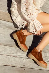 Bota corta color marrón óxido de cuero gamuzado, con plataforma de goma color beige y cierre frontal con cremallera.