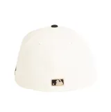 Gorra New Era modelo 59FIFTY de los Boston Red Sox, con diseño estructurado de visera plana. Presenta corona en color blanco roto (crudo), visera en tono tostado y bordado frontal en relieve con el logotipo del equipo en negro y detalles tostados.