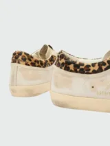 Zapatillas Golden Goose modelo Super Star, de diseño desgastado, con estrella lateral en gamuza marrón y detalle de animal print en el talón.