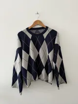 Sweater de punto con diseño de rombos en azul marino y gris, cuello redondo y mangas largas con corte holgado.