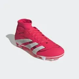 Championes de fútbol Adidas Predator Club, color fucsia con las tres tiras características en blanco. Presentan un cuello de corte medio para mayor estabilidad, exterior sintético con textura Strikeprint para control del balón y suela multiterreno con tapones blancos.