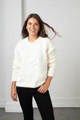 Buzo de punto color blanco, de corte holgado y cuello redondo, con diseño de flores aplicadas con detalles de mostacillas bordadas.