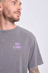 Remera de manga corta gris oscuro con efecto lavado y estampado tribal en la espalda. Corte oversize.
