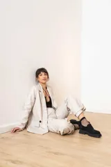 Blazer de cuero sintético color beige, con diseño de doble botonadura, solapas clásicas y bolsillos frontales con solapa.