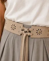 Faja ancha beige con diseño troquelado en forma de flores con tachas metálicas en el centro, y cierre frontal con cordones y tiras colgantes de gamuza.