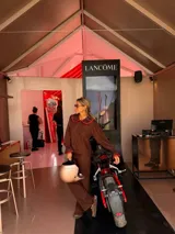 Camisa de color marrón chocolate con cuello Peter Pan y puños con volados, ambos detalles resaltados con un ribete en color rojo. Presenta cierre frontal con botones rojos.