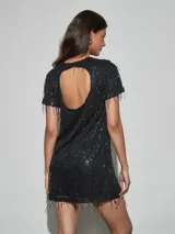 Vestido corto negro de manga corta, con cuello redondo y diseño completamente revestido de lentejuelas y flecos colgantes.
