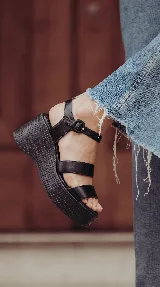 Sandalia de cuero marrón con plataforma corrida y taco alto texturizado. Posee tiras delanteras múltiples y una pulsera al tobillo con hebilla ajustable.