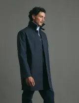 Gabardina clásica de corte recto, color beige, con cuello camisero, cierre frontal de botones y bolsillos laterales. Confeccionada en tejido técnico repelente al agua y al viento.
