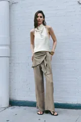 Pantalón de tiro medio con detalle de pareo superpuesto en la cintura y cierre de lazo lateral. Presenta pierna ancha y corte recto.