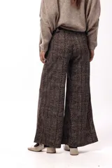 Pantalón de tiro medio-alto con silueta amplia y caída fluida. Presenta un diseño con estampado de espiga en tonos marrones y negros, bolsillos laterales y corte recto.