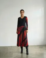 Vestido largo de corte fluido con escote en V y mangas largas. Presenta un diseño estampado con motivos de hojas en tonos rojos, terracota y borgoña sobre una base de color negro.