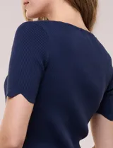 Blusa de punto acanalado color blanco, con escote cuadrado, mangas cortas y terminaciones festonadas en mangas y ruedo.