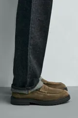 Mocasín de vestir para hombre, confeccionado en piel con acabado de serraje en color marrón oscuro. Presenta un diseño clásico con detalle de antifaz en el empeine, horma redonda y una suela track robusta de goma.