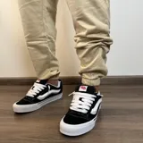 Pantalón tipo jogger de algodón color beige, con puños elásticos en los tobillos y estampa pequeña en el frente con el texto 'BUENA VIBRA EST. 2018'.