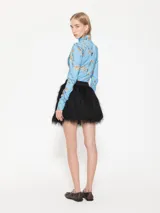 Minifalda negra con flecos de hilo y cintura de tela lisa.