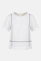 Blusa blanca de lino de manga corta, con cuello redondo y detalles de costuras decorativas bordadas en color azul y rojo en el frente.