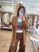 Saco largo color crema, de tejido de punto, con bolsillos laterales y corte recto.