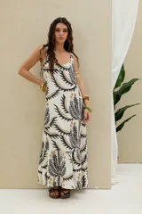 Vestido largo de color blanco con estampado gráfico en tonos negros y dorados, sin mangas y con escote redondo.