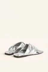 Sandalia tipo slide de cuero vacuno color blanco, con diseño de tiras cruzadas y fruncidas. Presenta una puntera cuadrada y una suela plana de cuero con un pequeño taco de 2 cm.