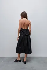 Falda midi de efecto cuero color negro, con corte evasé, tiro alto y diseño con recortes horizontales. Posee cierre lateral oculto.