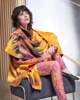 Capa asimétrica multicolor de lana merino afieltrada, teñida artesanalmente con acuarelas en tonos amarillos, naranjas, azules y violetas.