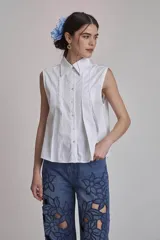 Camisa azul marino sin mangas con cuello clásico, abotonada al frente y detalle de plisados verticales en el pecho.