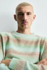 Jersey de punto con ajuste relajado, cuello redondo y manga larga. Presenta un diseño de rayas horizontales difuminadas en tonos verde agua y marrón, con acabados en rib en cuello, puños y ruedo.