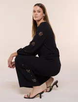 Blusa azul de corte holgado y fluido, con escote en V y mangas largas raglán que presentan detalles de calados con forma de flores y puños elastizados.