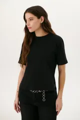 Remera negra de corte recto con detalle de aros metálicos en los laterales.