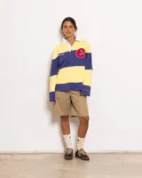 Buzo estilo rugby de manga larga, con cuello polo blanco y cierre parcial de botones. Presenta un diseño a rayas horizontales anchas en amarillo y azul oscuro. Lleva un parche bordado con una 'C' en el pecho y la inscripción 'COOLWAY' en el área del pecho.