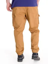 Pantalón cargo color tostado, con bolsillos laterales tipo cargo, cintura elástica y puños elásticos en los tobillos.