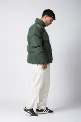 Campera puffer de corte relajado en color verde oscuro, con cuello alto, cierre frontal completo y logo bordado en el pecho.