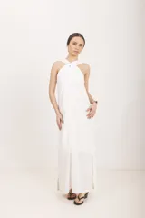 Vestido largo blanco de corte recto con diseño halter cruzado en el cuello y aberturas laterales en el bajo.