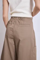 Pantalón palazzo color marrón claro, de tiro alto, con pinzas y bolsillos laterales.